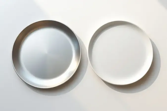 Comparação visual conceitual entre superfícies de titânio e cerâmica para chapinhas, destacando as diferenças de material e acabamento.